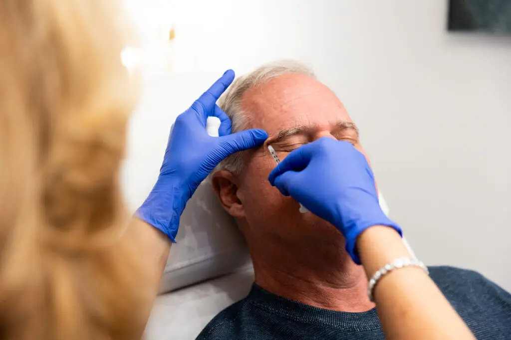 A man lies down as a provider injects Brotox in Greensboro into his forehead.
