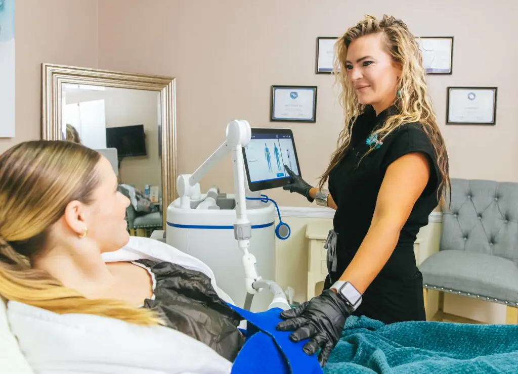 A female Restoration MedSpa provider, wearing black scrubs, a purple silicone watch, and black gloves, administers CoolSculpting Elite body contouring in Winston-Salem. CoolSculpting permanently reduces fat by freezing fat cells.