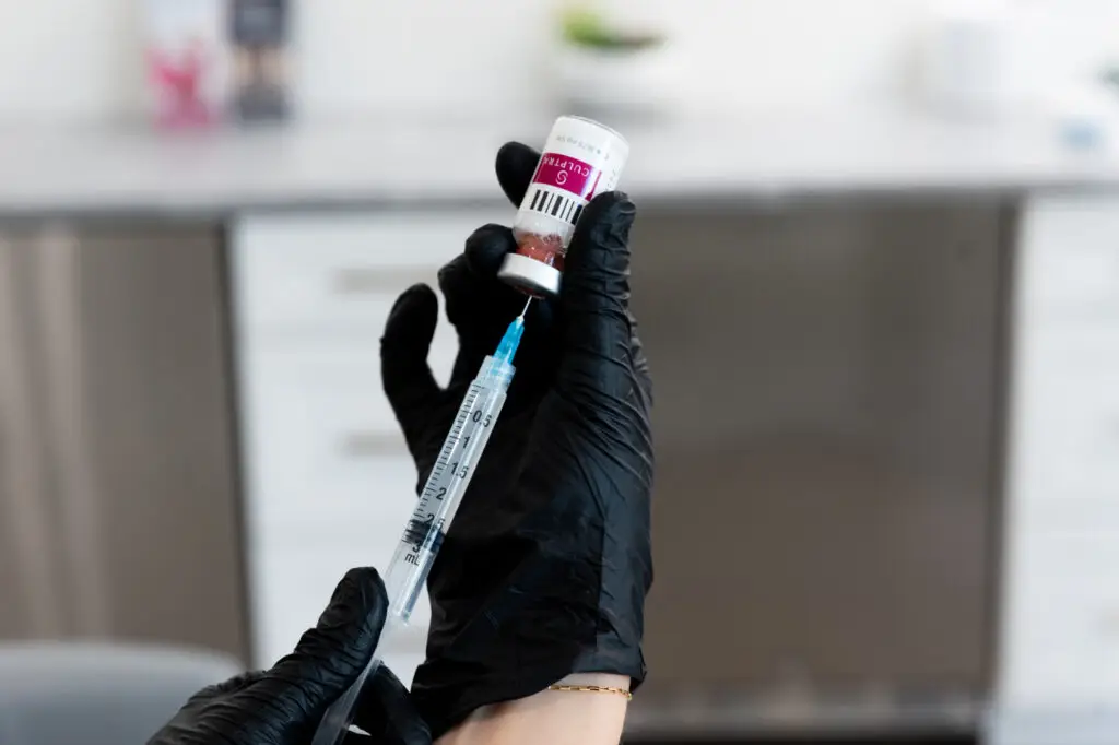 A Restoration MedSpa medical provider wearing black gloves, prepares a Sculptra injection. One of many collagen injections in Greensboro, Sculptra rejuvenates skin for a youthful glow.